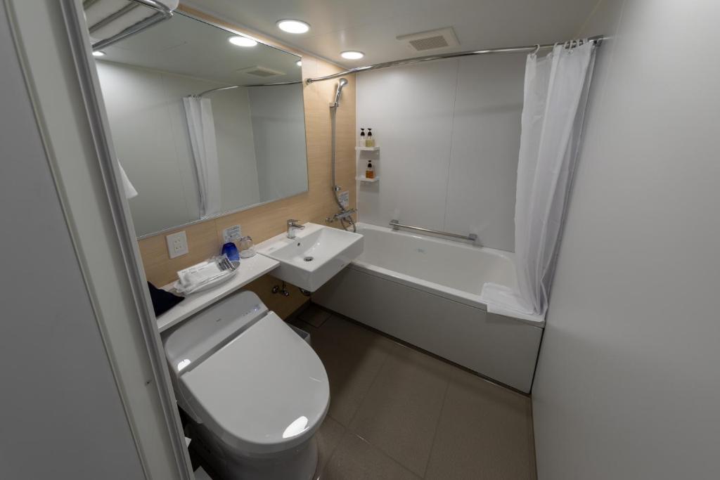 a bathroom with a toilet and a sink and a mirror at Iroha Grand Hotel Kintetsu Nara Ekimae in Nara