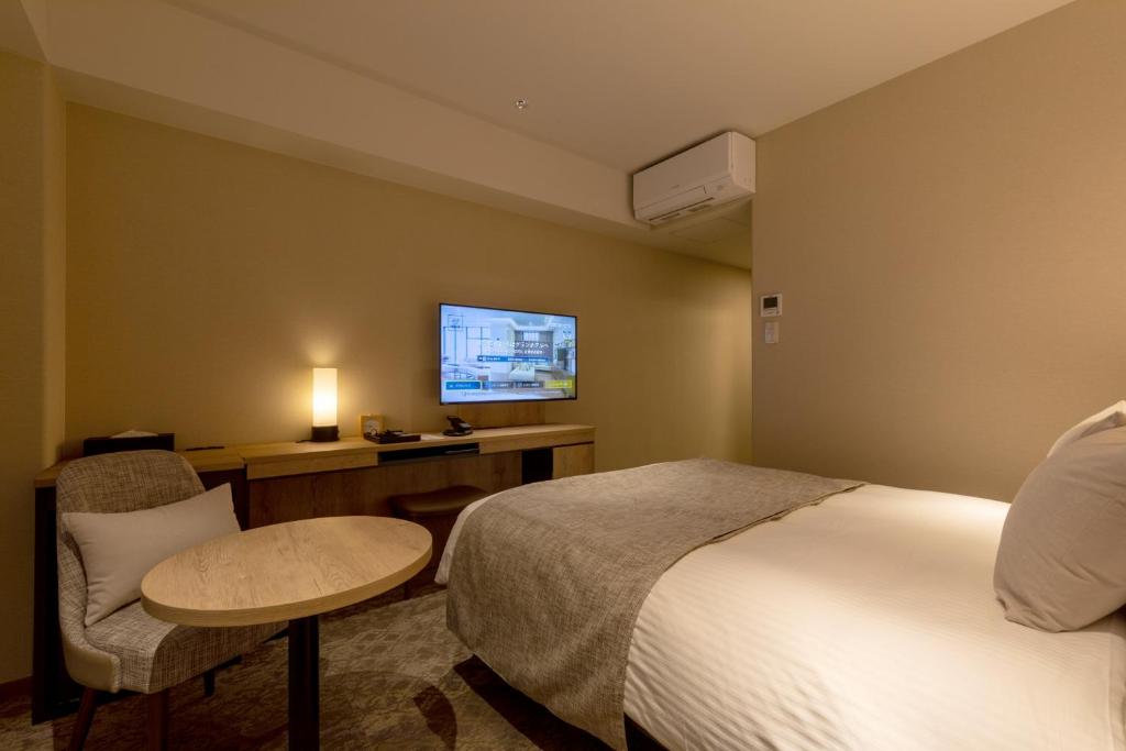 a hotel room with a bed and a table and a tv at Iroha Grand Hotel Kintetsu Nara Ekimae in Nara