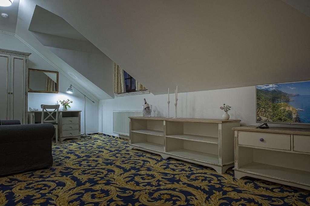 a living room with white furniture and a staircase at Hotel Pod Bránou in Bardejov