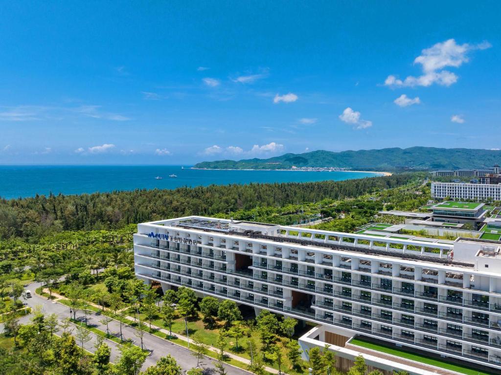 Sanya Haitang Bay Moutai Resort Superior Hotel في سانيا: اطلالة هوائية على مبنى مع المحيط في الخلفية