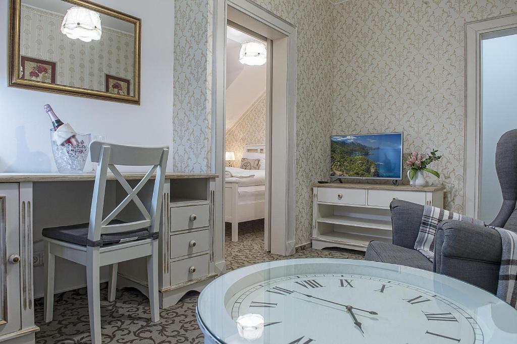 a living room with a clock and a table at Hotel Pod Bránou in Bardejov