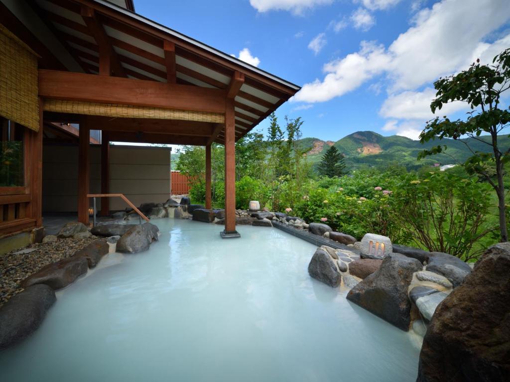 a pool of water with rocks in front of a house at Zao Shiki no Hotel in Zao Onsen