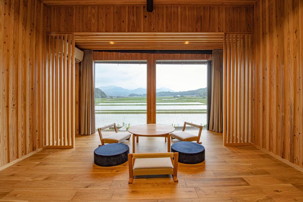 UsaGLOCE宇佐 田宮-田んぼのお城- l 美しい田園と山々を一望 癒しと伝統を体感的一间有桌子、椅子和大窗户的房间