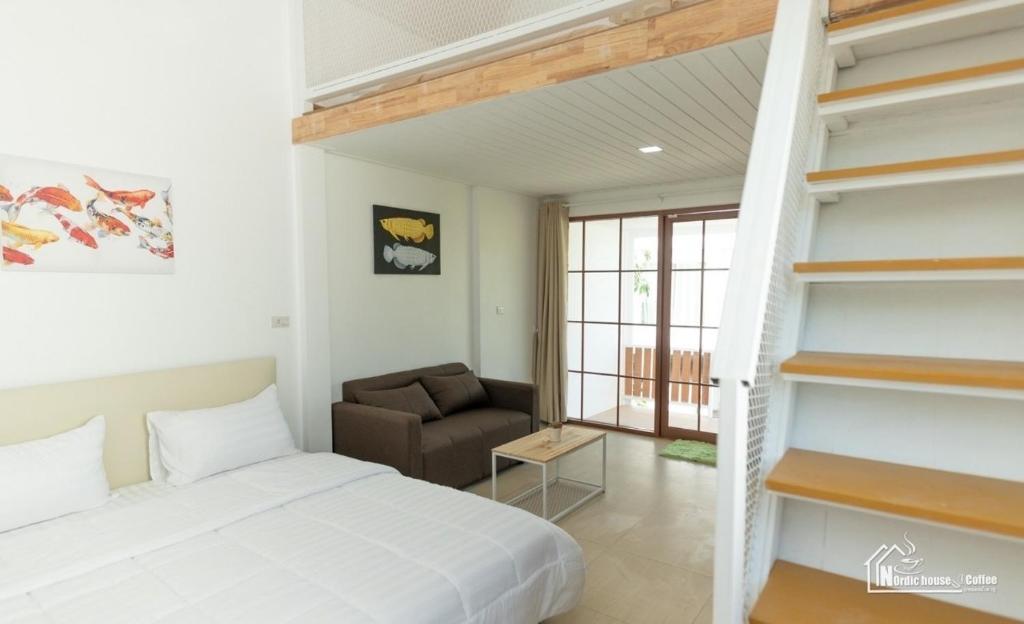 1 dormitorio con 1 cama, 1 silla y una escalera en นอร์ดิกเฮ้าส์ แอนด์ คอฟฟี่หนองบัวลำภู en Ban Huai Luk