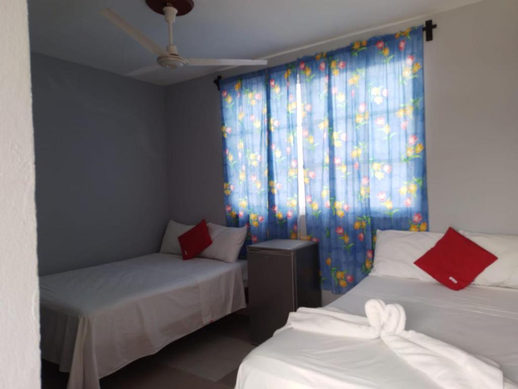 a room with two beds and a window with curtains at Hotel María Inés in Veracruz