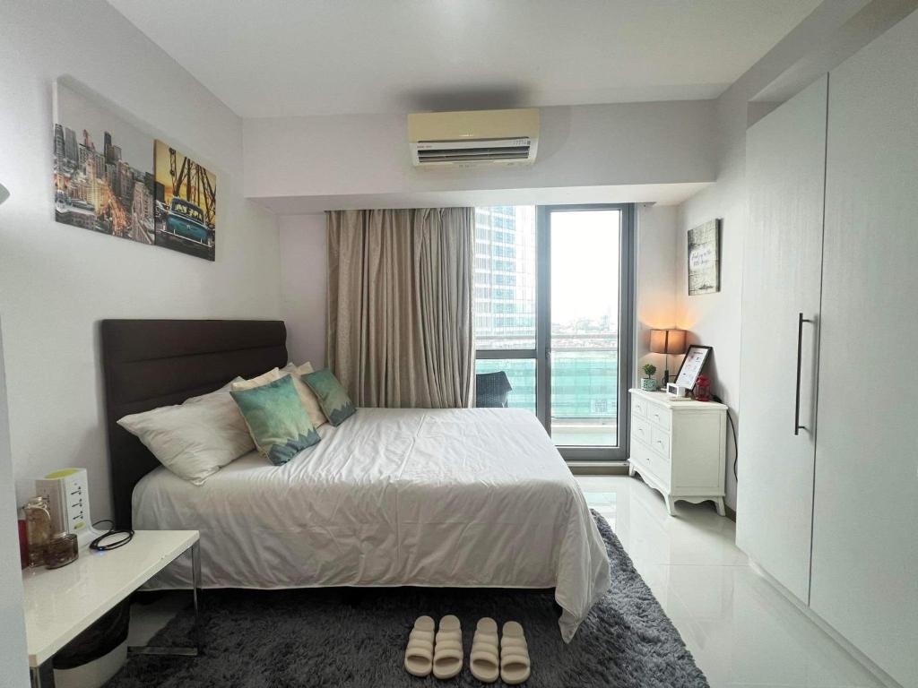 a bedroom with a bed and a large window at Sakura House in Manila