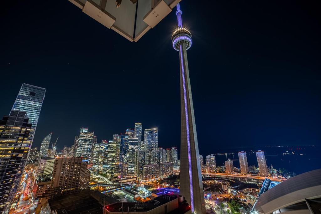 una vista de la aguja espacial por la noche en Designer condo w/ CN Tower view & parking en Toronto
