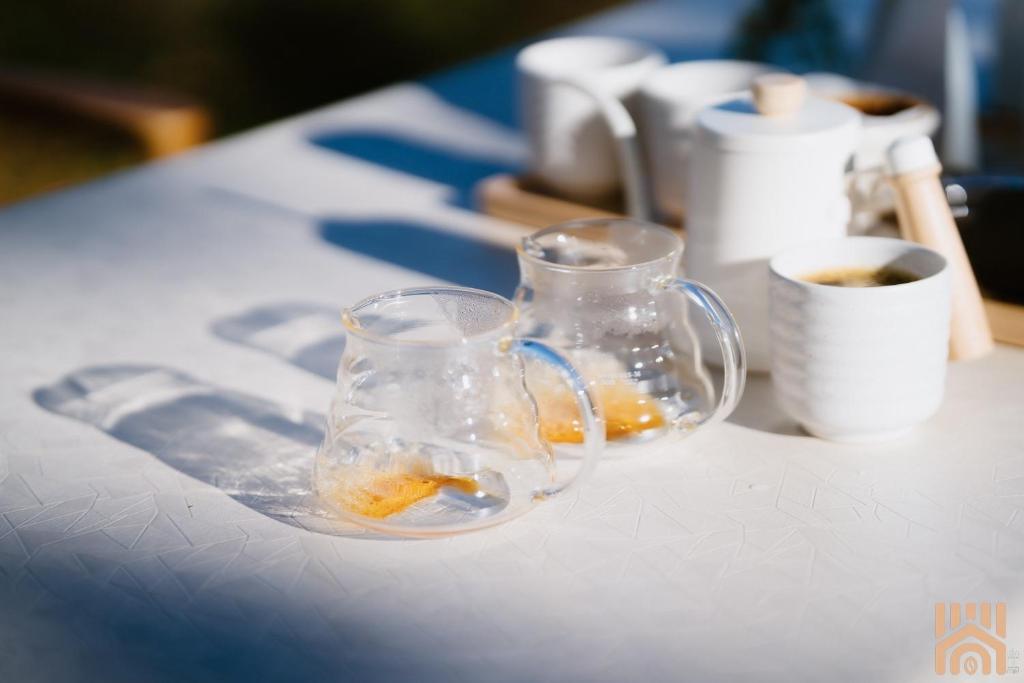 duas canecas de vidro sentadas numa mesa com uma chávena de café em Arabica lodge em Ban Huai Khai