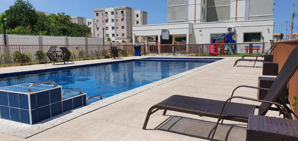 a swimming pool with a bench next to a building at Lindo apartamento no Litoral Norte in Camaçari