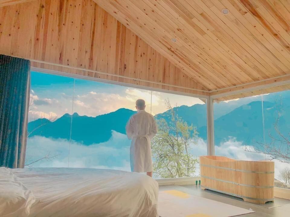 a man standing in a room with a large window at Daisy Sapa - Homestay - Panorama in Lao Cai