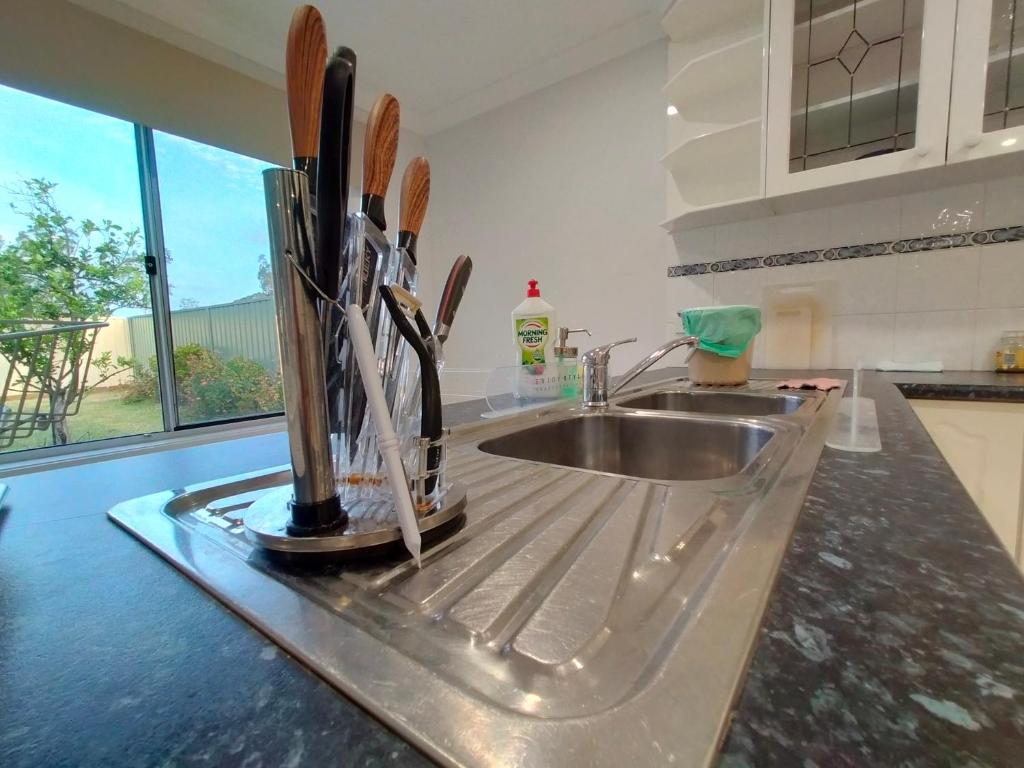 encimera de cocina con fregadero y perchero para cuchillos en 4 Bedroom, 3 bath room home in Kingswood NSW, free WIFI Internet, free parking, en Kingswood