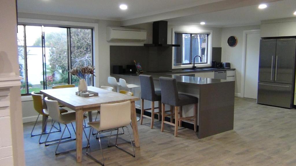 a kitchen with a wooden table and a kitchen island with chairs at East Coast Hideaway Beach Retreat in Orford