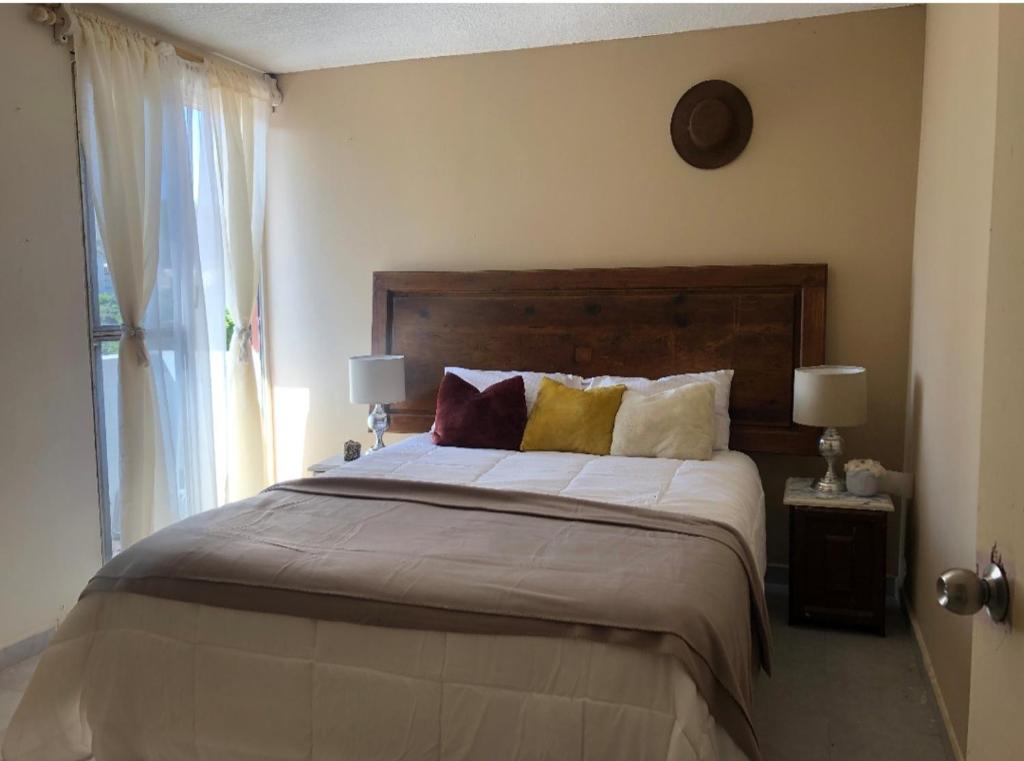 a bedroom with a large bed with two lamps and a window at Marbella in Irapuato