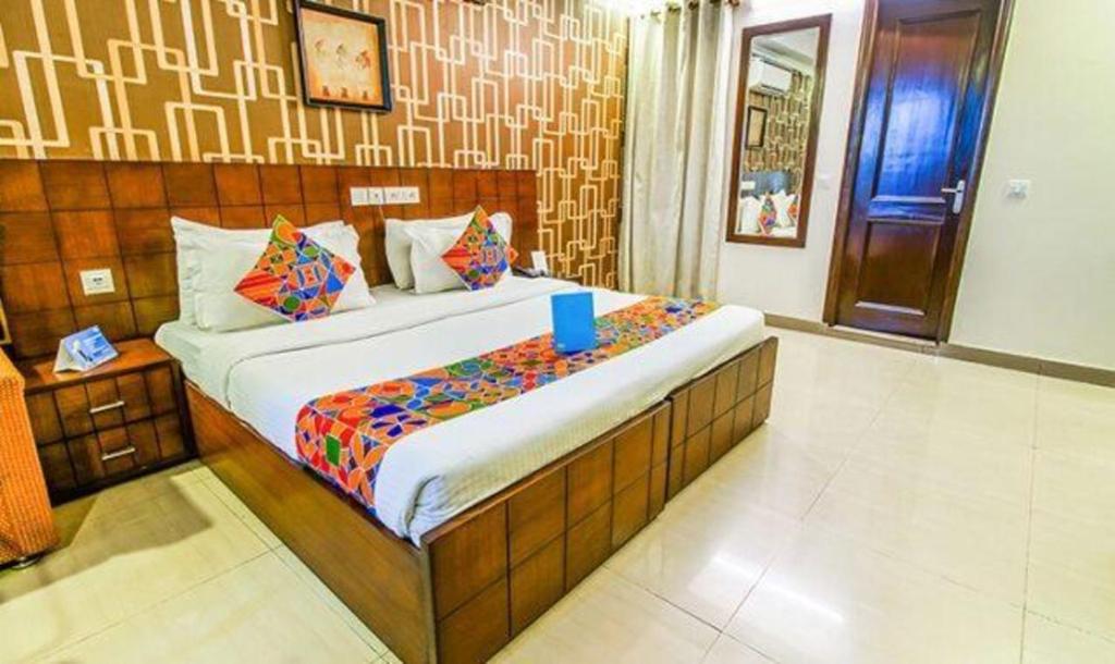 Un dormitorio con una cama con una taza azul. en FabHotel SP Plaza Greater Kailash, en Nueva Delhi