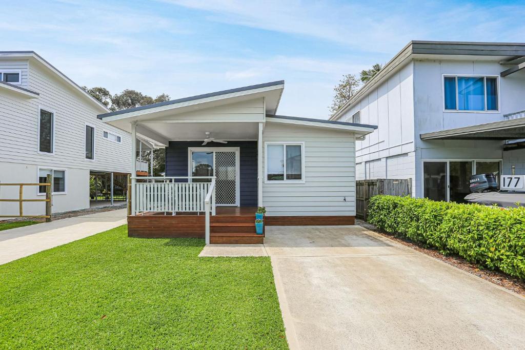 a white house with a porch and a driveway at Tea Gardens Cosy Cottage in Tea Gardens