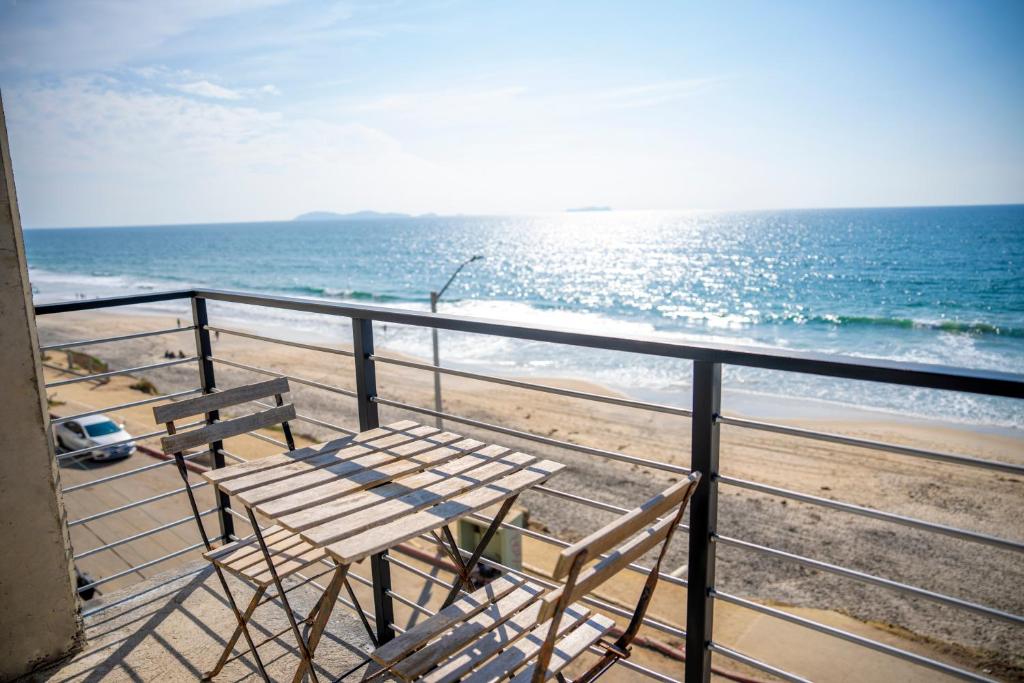 a table and chairs on a balcony overlooking the beach at Beachfront, sun, sand & fun - Cozy 1 Bdr Apt in Tijuana