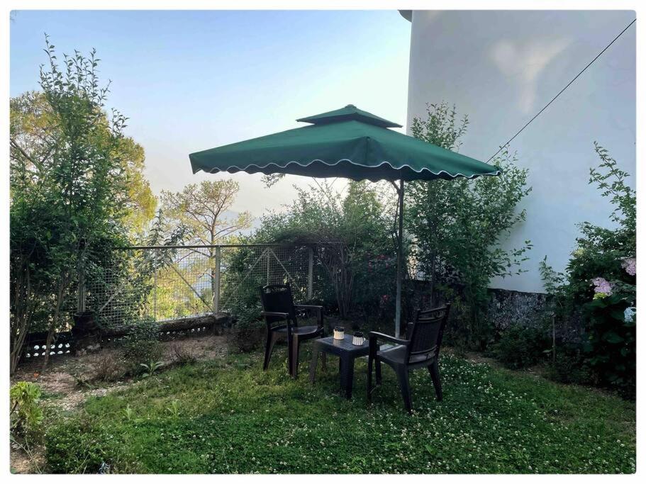 een tafel en stoelen onder een groene parasol bij 2 Bedroom Pine View Cottage with Lawn in Nainital