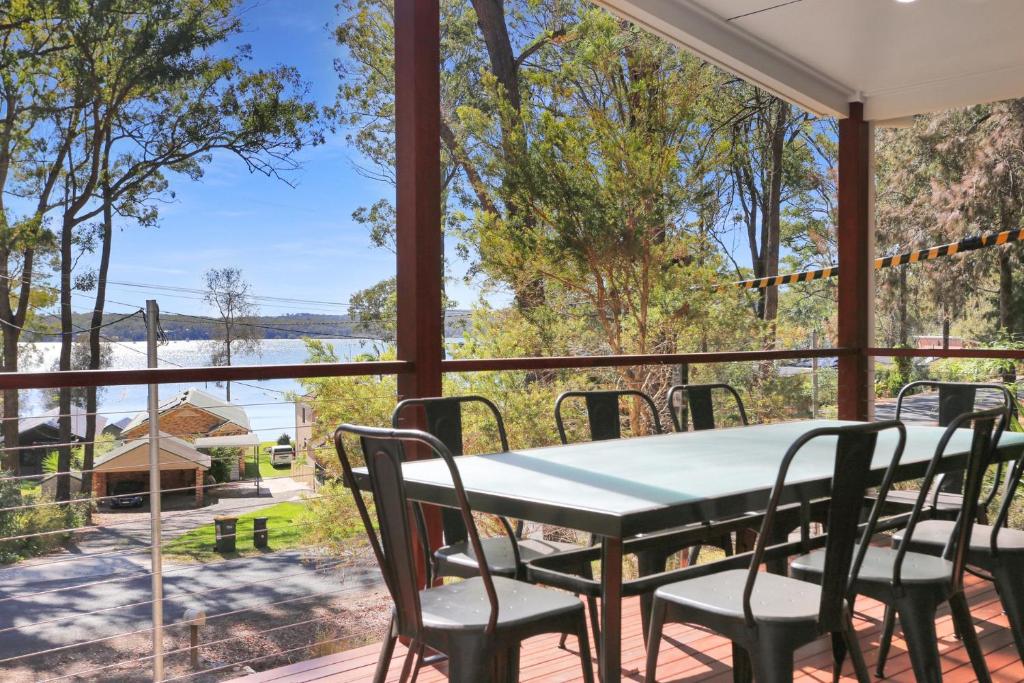 a table and chairs on a porch with a view of the water at Wylah in North Arms Cove