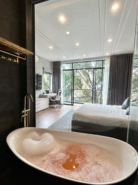 a bathroom with a bath tub with a bed in the background at Khánh Nguyễn Luxury Apartment, balcony street view, large bathtub in Ho Chi Minh City