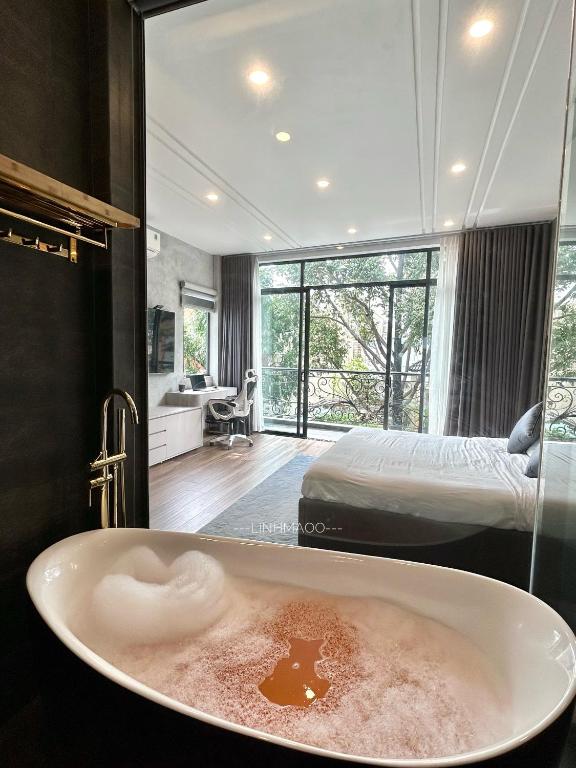 a bathroom with a bath tub with a bed in the background at Khánh Nguyễn Luxury studio, balcony street view, large bathtub in Ho Chi Minh City