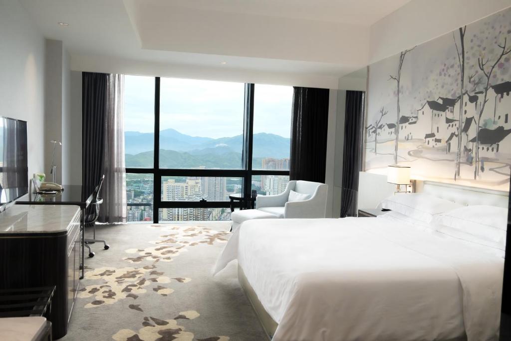 een hotelkamer met een bed en een groot raam bij Huaqiang Plaza Hotel Shenzhen, Enjoy Complimentary Afternoon Tea & Mini Bar & Night Snack in Shenzhen