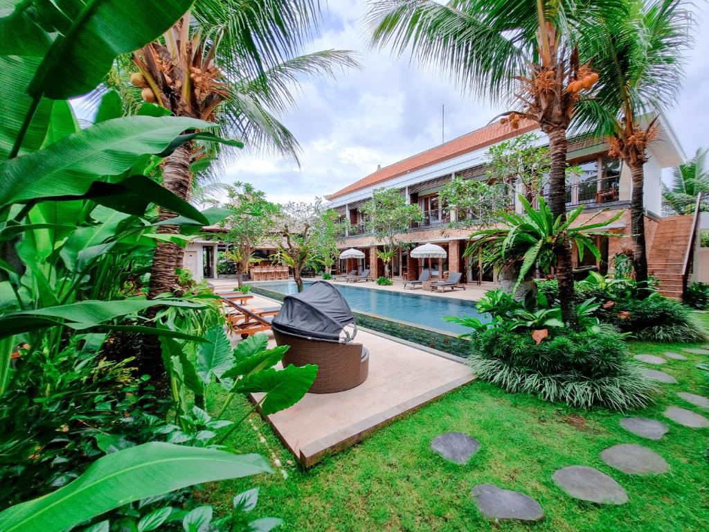 un complejo con piscina y palmeras en Kahayana Suites Ubud en Ubud