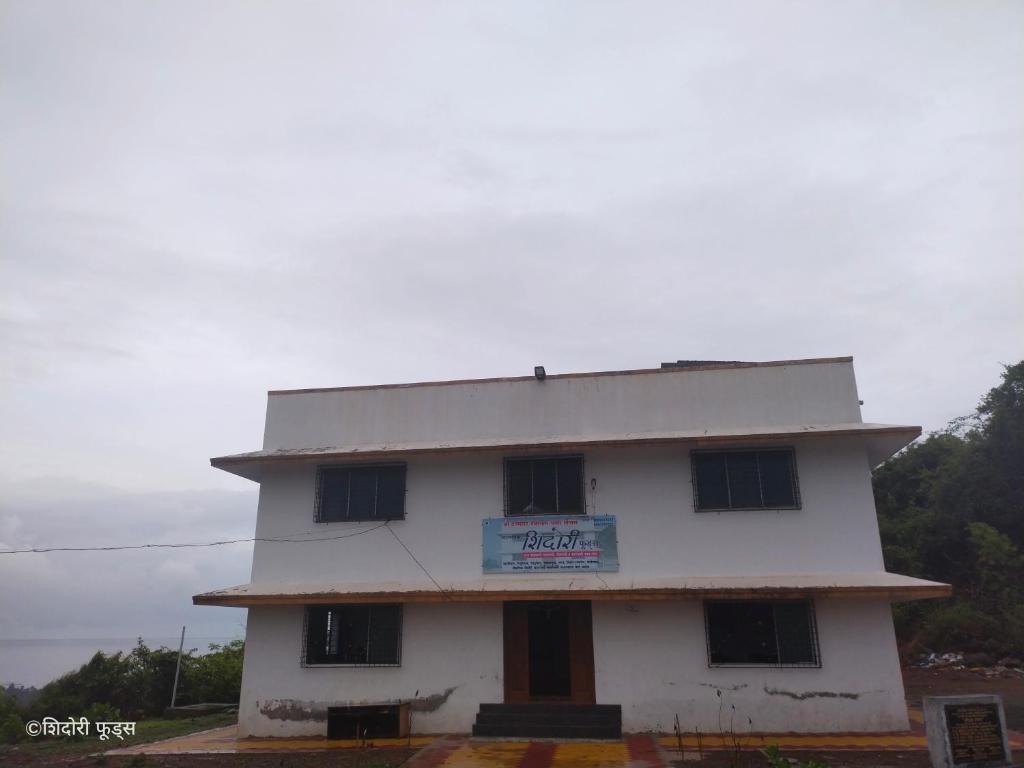 a white building with a sign on it at Shidori Foods in Murud
