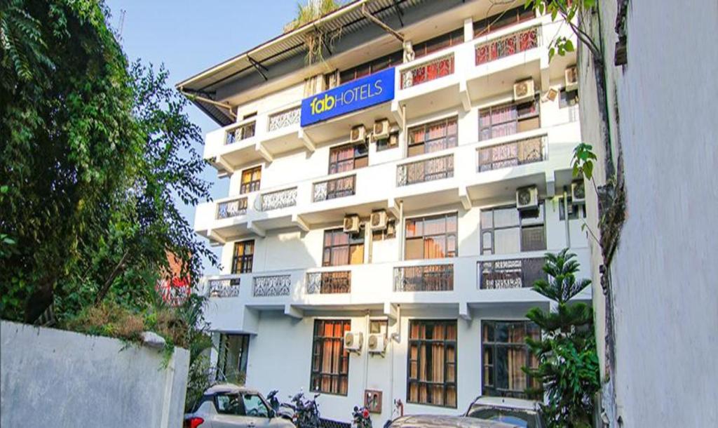 a large white building with a blue sign on it at FabHotel CP Palace Race Course in Dehradun