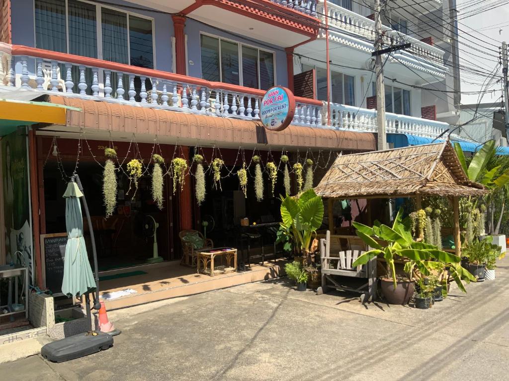 um edifício com um guarda-chuva e plantas à sua frente em Ban Por Fai em Cha Am