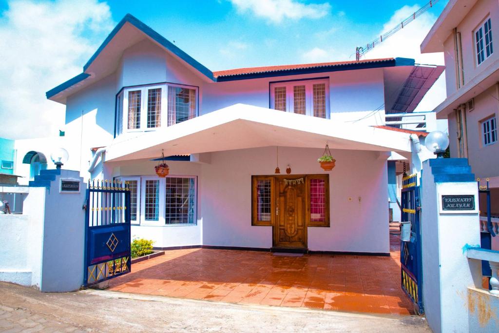 Casa blanca con puerta y porche en Priyadeep BnB en Ooty