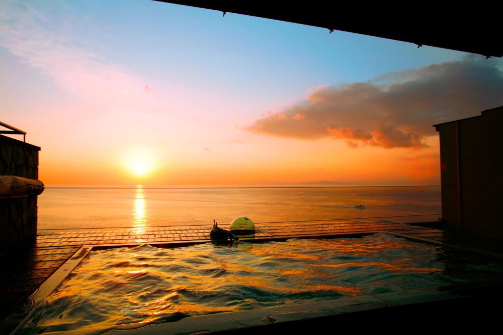 a sunset over the ocean with a swimming pool at 海のほてる　いさば in Numazu