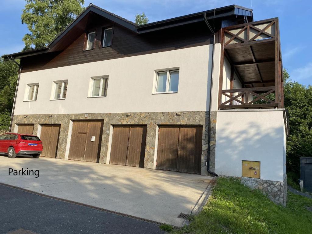 una casa con puertas de madera y un coche rojo en Ager Apartments, en Dolný Smokovec