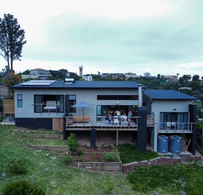 a house with a large deck with people sitting on it at Eden on Edwards - no more loadshedding! in Knysna