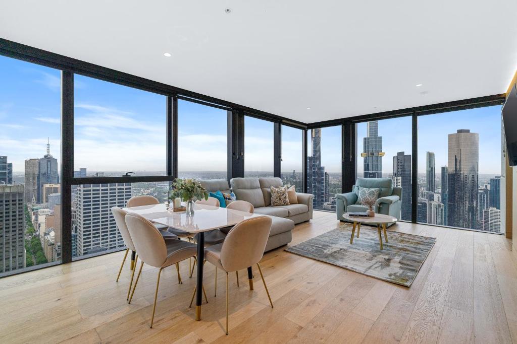 een woonkamer met een bank en een tafel en stoelen bij Collins House Apartments by CLLIX in Melbourne