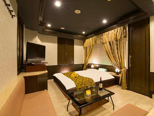 a bedroom with a bed and a couch and a tv at かぼちゃの馬車 泉大津大人専用 in Izumiotsu