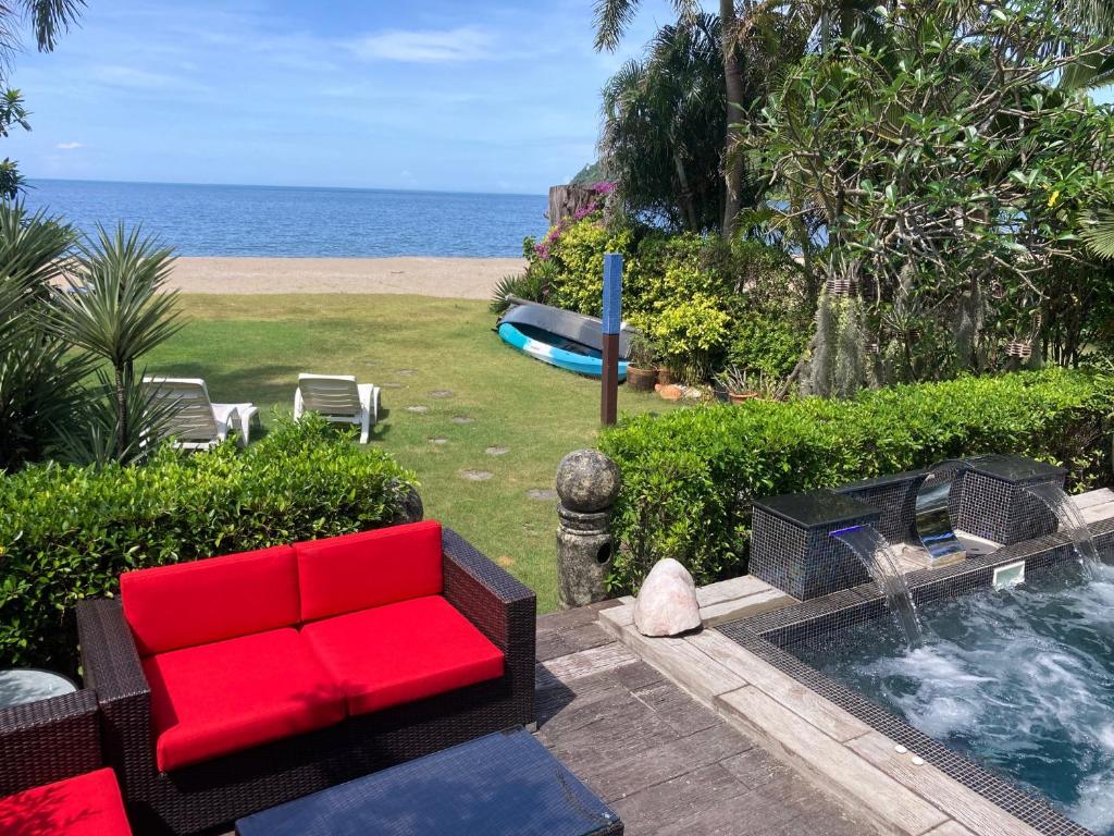a red couch sitting next to a pool next to the ocean at Elegant Horizons in Ko Chang