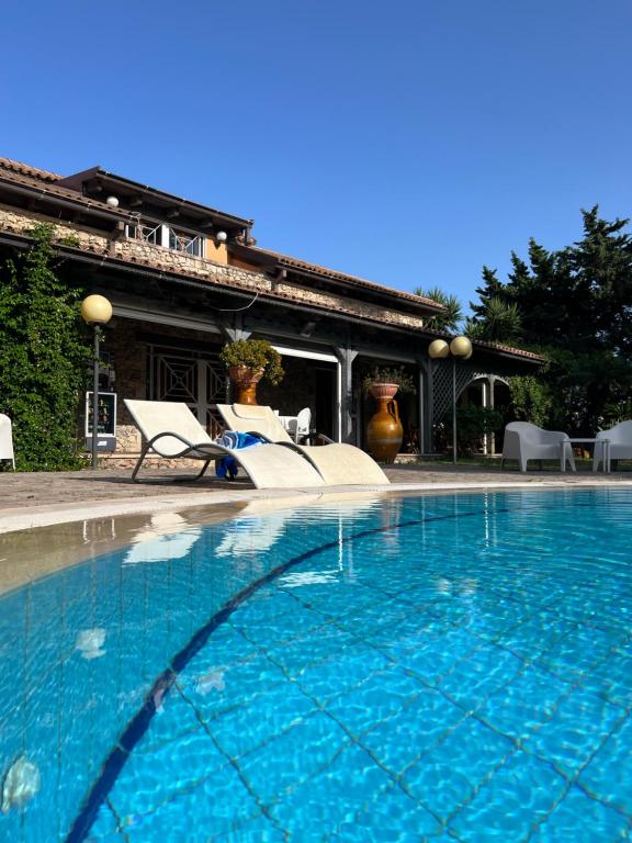 una piscina con due sedie e una casa di All'Ombra del Palmeto a Taranto