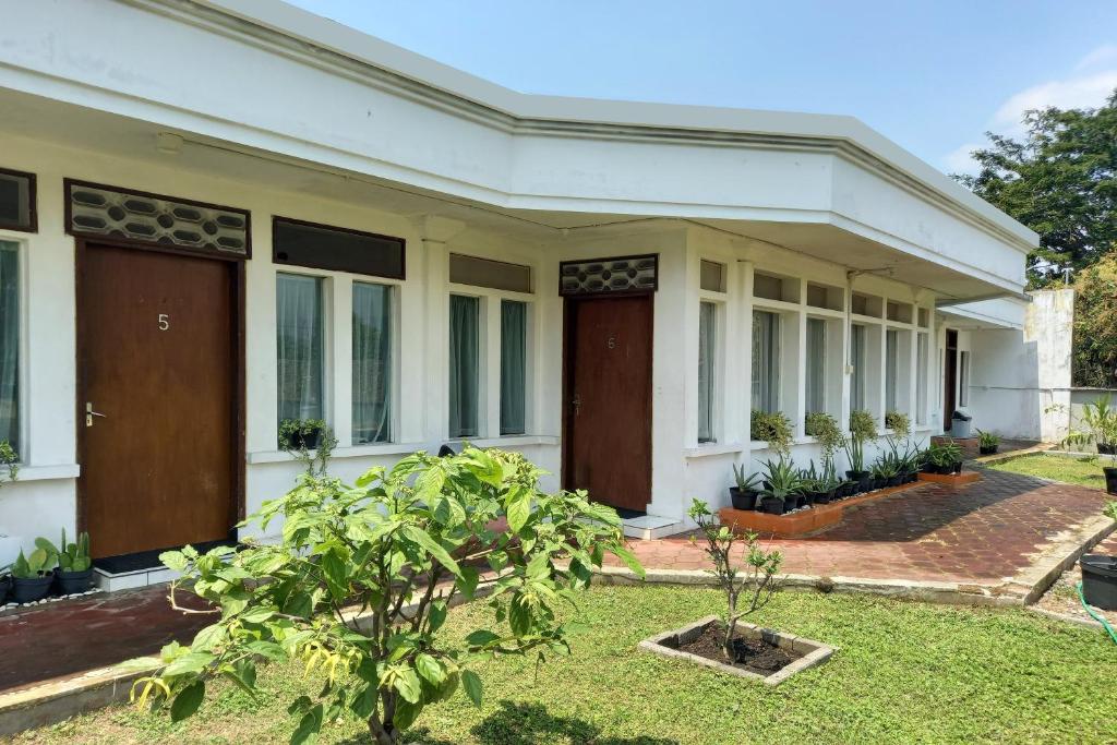 een wit huis met bruine deuren en een tuin bij Vanda Villa in Batu