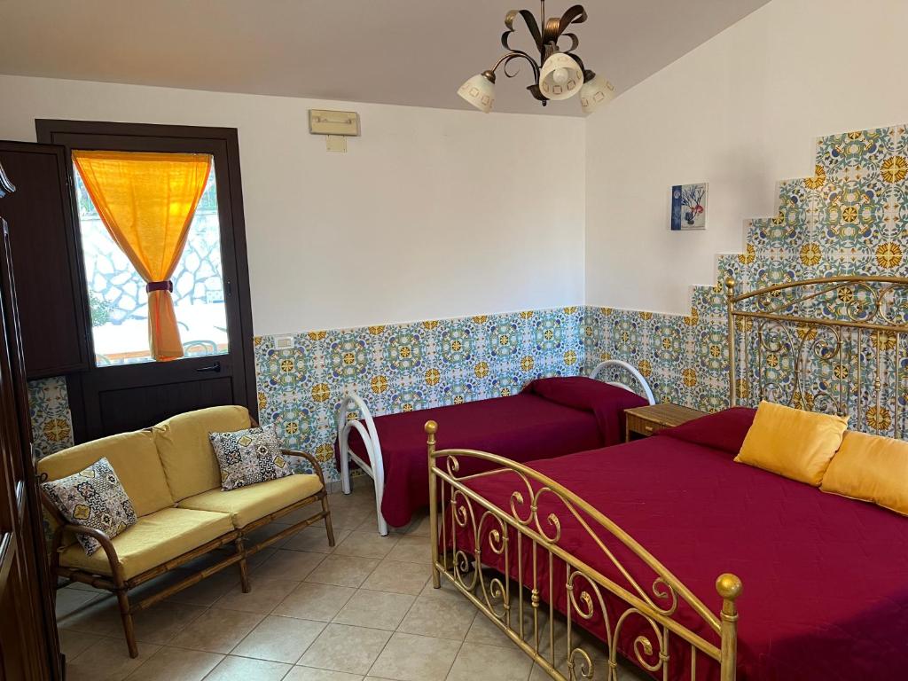 um quarto com uma cama, um sofá e uma janela em Baglio Cracchiolo da Tuzzo - Casa Fico D'India em San Vito lo Capo