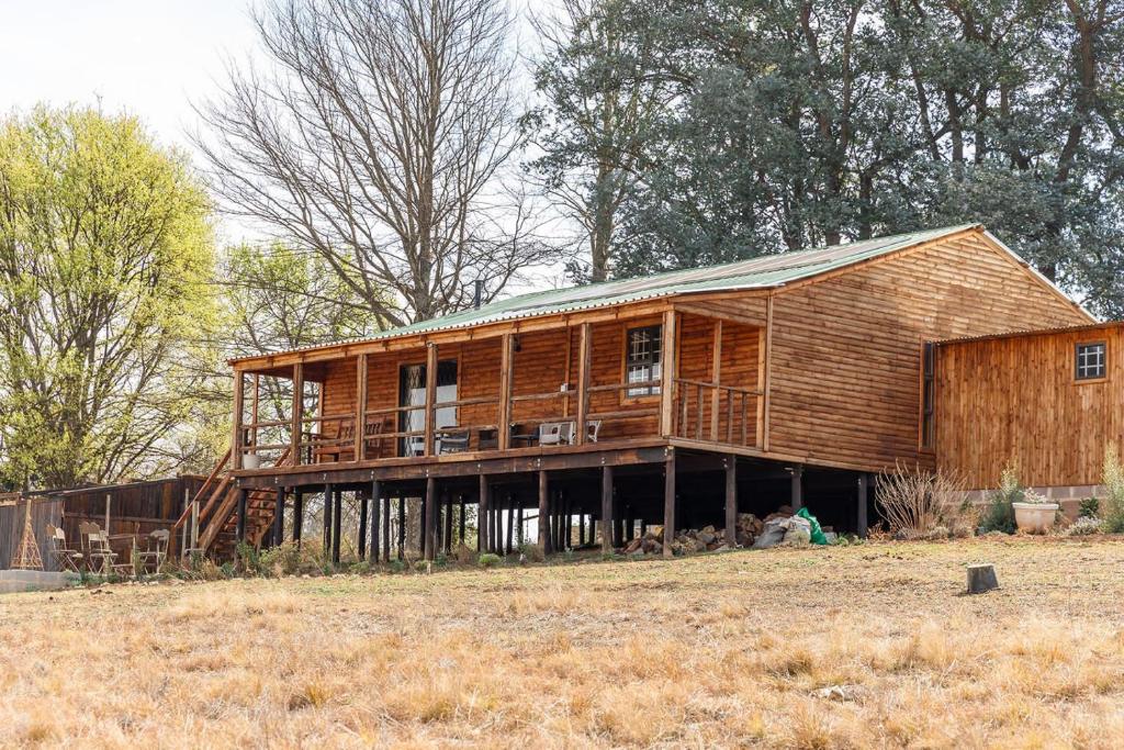 duży drewniany dom siedzący na szczycie pola w obiekcie Fireside Cabin w mieście Underberg