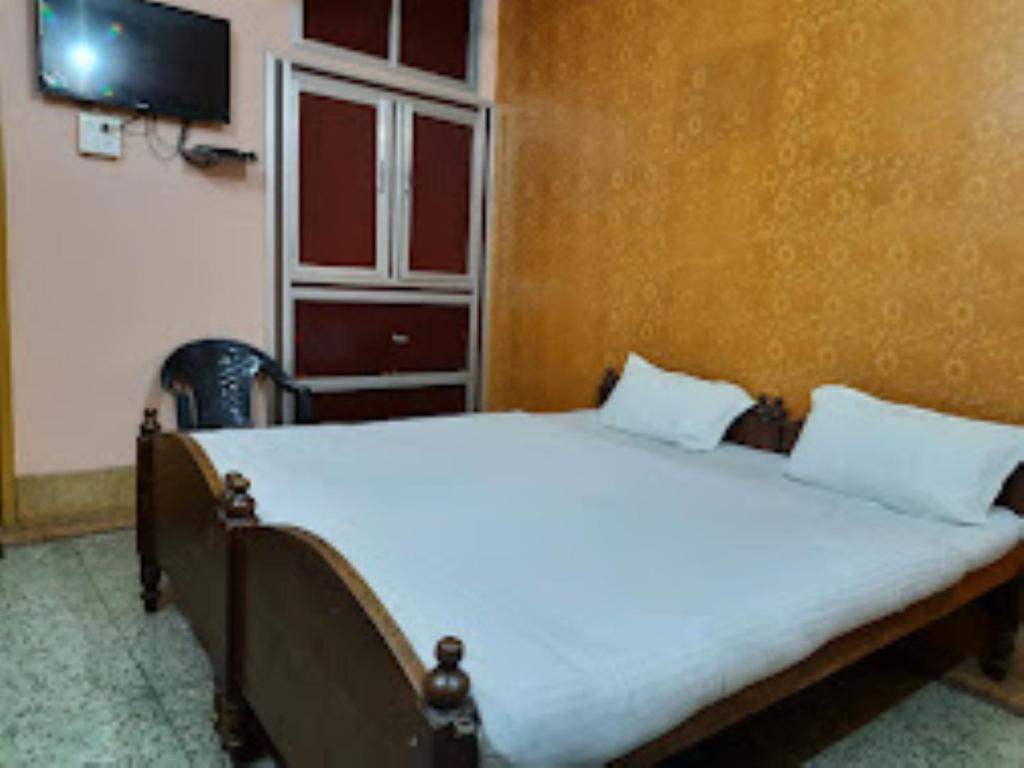 a bedroom with a large bed with white sheets and a tv at Hotel santi vihar,Jehanabad in Jahānābād