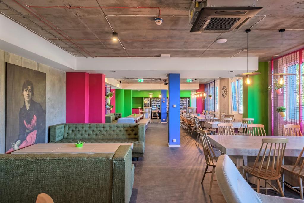 Easy One Premium Art Hostel في كراكوف: مطعم به طاولات وكراسي وجدران ملونة