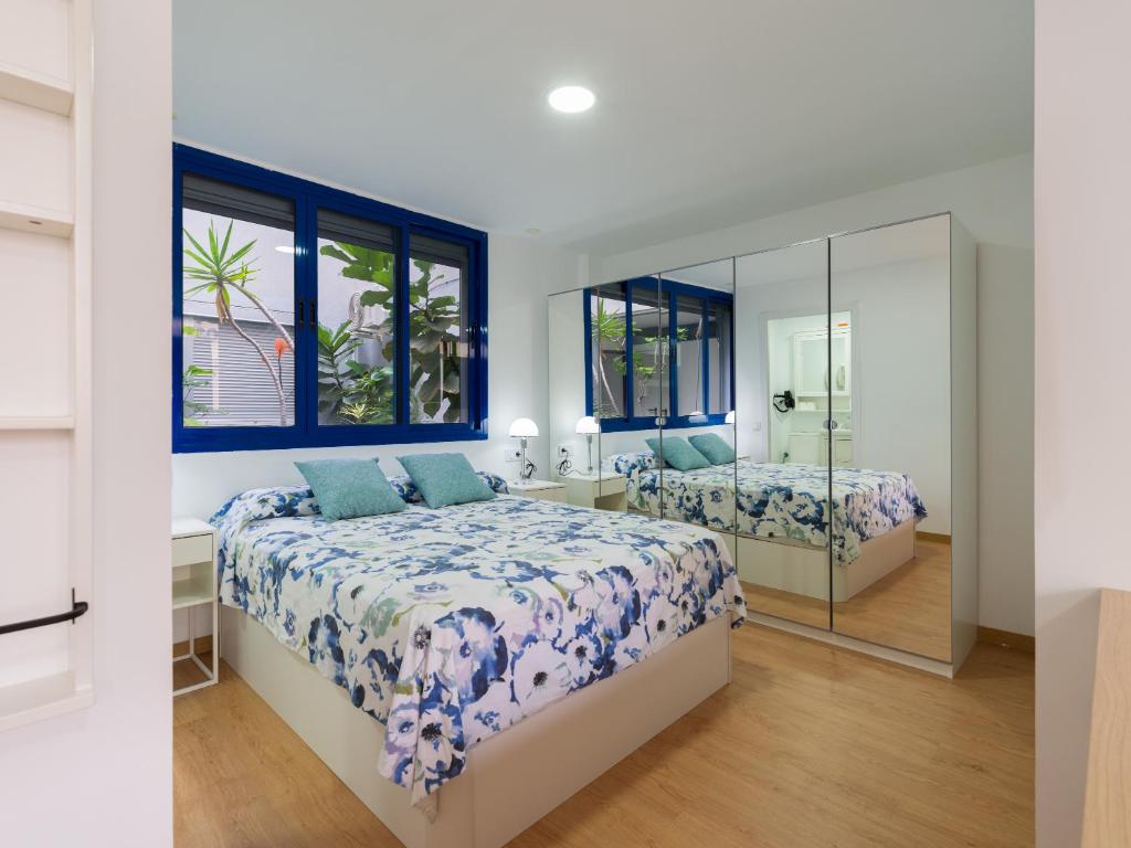 Un dormitorio con dos camas y un espejo. en Suites Garden DALI 14, en Las Palmas de Gran Canaria