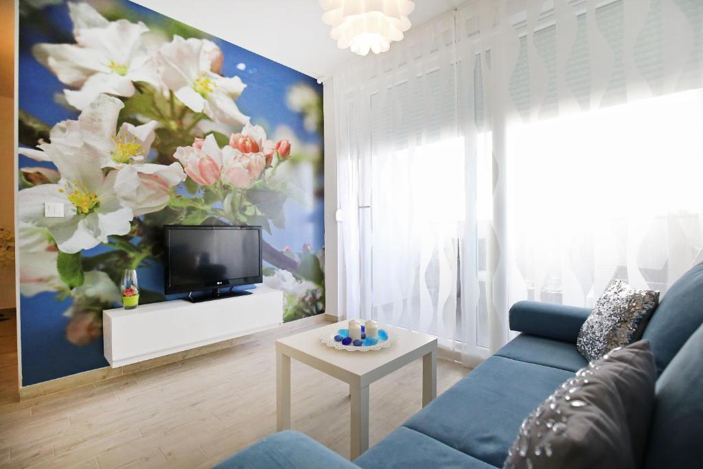 uma sala de estar com um sofá azul e um quadro de flores em Apartment Flowers em Zadar