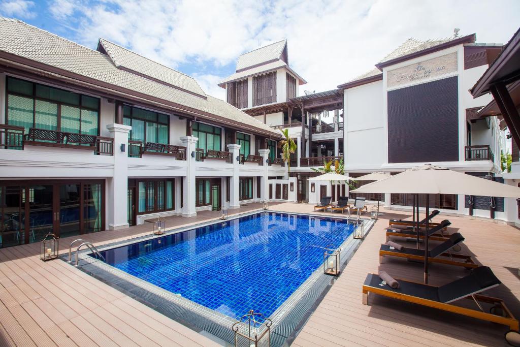 a swimming pool with chairs and an umbrella next to a building at Huernnana Boutique Hotel in Phrae