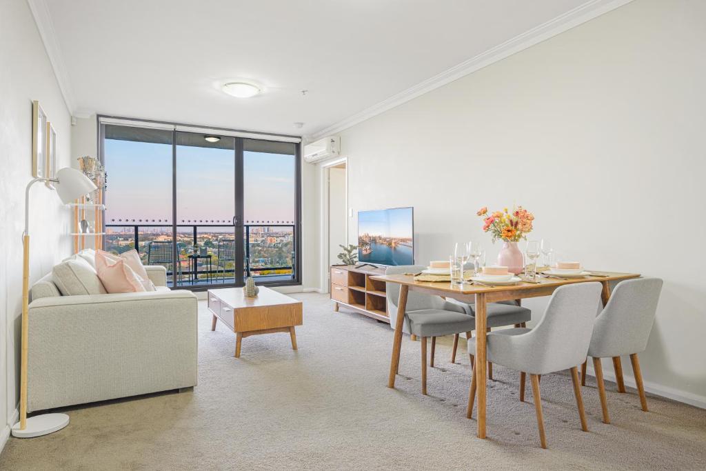 a living room with a dining room table and a couch at Parramatta lovely 2br near station with City view in Sydney