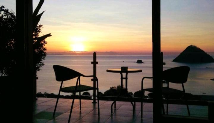 una puesta de sol sobre el océano con sillas y una mesa en Hotel Sanset, en Labuan Bajo