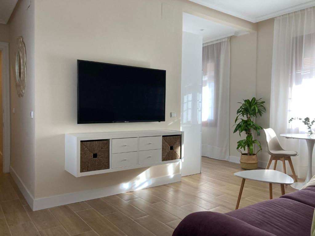 uma sala de estar com uma televisão de ecrã plano na parede em Ciudad del Encaje 3 em Almagro