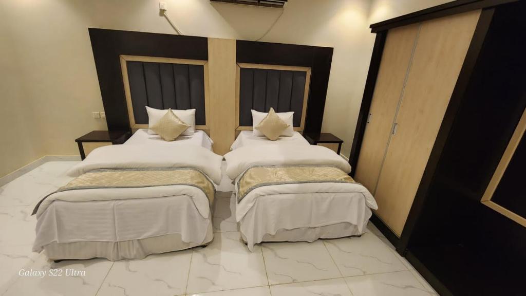 2 letti con lenzuola e cuscini bianchi in una stanza di برج رفيف a Baish