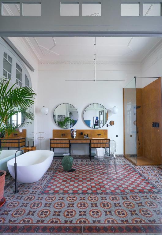 a bathroom with a tub and a table and mirrors at Aristide Hotel - Small Luxury Hotels of the World in Ermoupoli
